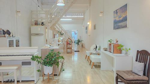 a white room with a piano and tables and chairs at Najai boutique house ที่พักลำพูน in Lamphun