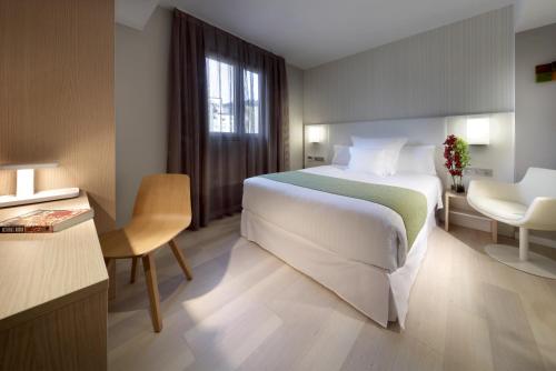 a hotel room with a large bed and a desk at Barceló Bilbao Nervión in Bilbao