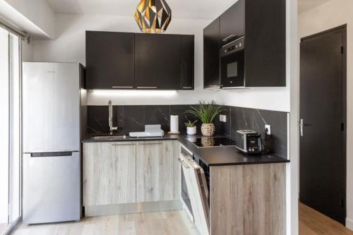 - une cuisine avec des armoires noires et un réfrigérateur blanc dans l'établissement Le Mimosa - Calm - Spacious - 200m from the sea - Parking, à Cagnes-sur-Mer