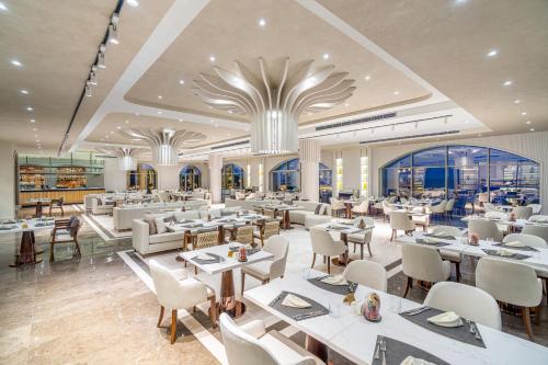 a restaurant with white tables and chairs and windows at Merit Royal Premium Hotel Casino & SPA in Kérynia