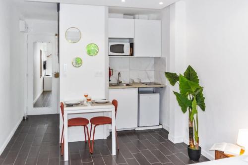 La cuisine est équipée d'une table, de deux chaises et d'un réfrigérateur. dans l'établissement L'Emeraude - Calm - Beach - WIFI, à Antibes