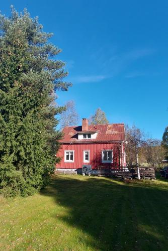 a red house with a red roof and a tree at Morsgården in Stöllet