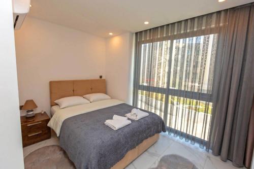 ein Schlafzimmer mit einem Bett und einem großen Fenster in der Unterkunft Cruise 2Bed Apt in Central Kyrenia in Luxury Complex by HolidayKeys in Kyrenia