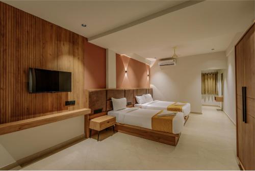 コーリコードにあるHotel Beverly Plaza Kozhikodeのベッドと薄型テレビのある寝室