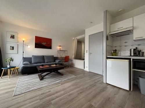un salon avec un canapé et une cuisine dans l'établissement Appt Studio cabine - LA ROCHELLE - LR250-A102, à La Rochelle
