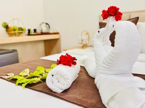 two white towels with red flowers on a bed at EIT Masky Villa in Ambalangoda
