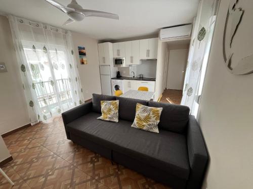 salon z czarną kanapą i kuchnią w obiekcie Apartamentos MareaBeach w mieście Torremolinos