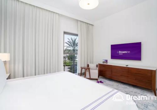 a bedroom with a bed and a flat screen tv at Dream Inn - Address Beach Residence - Luxury Apartments in Fujairah