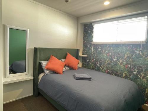 a bedroom with a bed with orange pillows and a mirror at Aura two bedroom1 living room Wifi ,balcony, harbor view, easy parking 1404 in Auckland