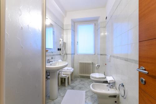 a white bathroom with a toilet and a sink at Hotel Garni Le Corti in Grosotto
