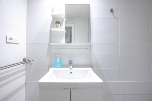 une salle de bain blanche avec un lavabo et un miroir dans l'établissement Apartamento Puerta Cartago 1 by CartagenaSpain, à Carthagène