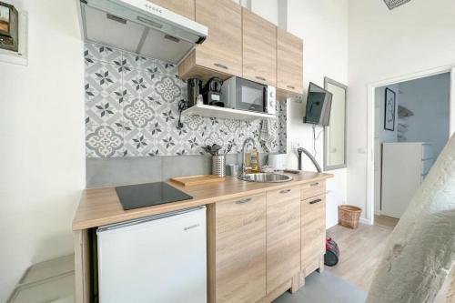 Elle comprend une petite cuisine avec des placards en bois et un évier. dans l'établissement Flexliving - Studio - Charlot, à Paris
