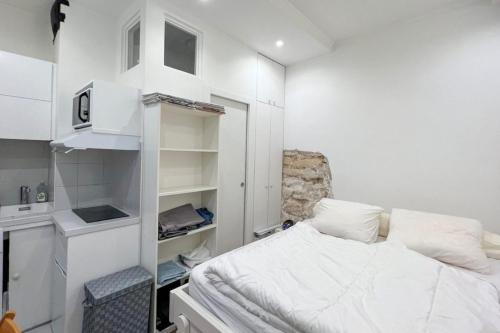 Cette petite chambre blanche dispose d'un lit et d'étagères. dans l'établissement Flexliving - Studio - Gérard, à Paris