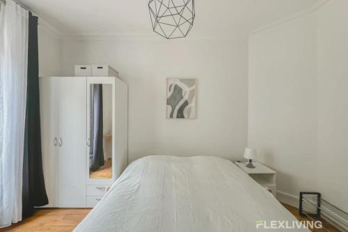 une chambre blanche avec un lit et un miroir dans l'établissement Flexliving - room - Sophie Germain, à Paris