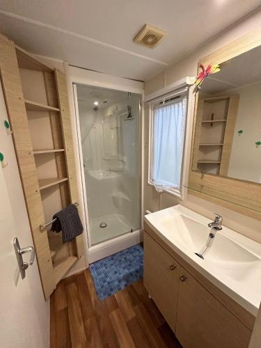 une salle de bain avec un lavabo blanc et une douche dans l'établissement Mobil home finistère sud 2CH 4PERS, à Clohars-Carnoët