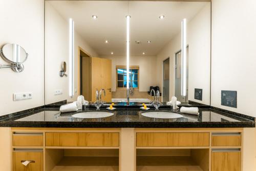a bathroom with two sinks and a large mirror at Berghotel Rehlegg in Ramsau