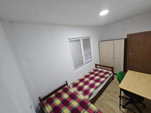 ein Schlafzimmer mit einem Bett, einem Tisch und einem Fenster in der Unterkunft Avtokomanda in Skopje