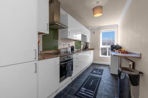 Una cocina con gabinetes blancos y una ventana grande. en 1 Double Room in Shared apartment in Central Edinburgh with free parking, en Edimburgo