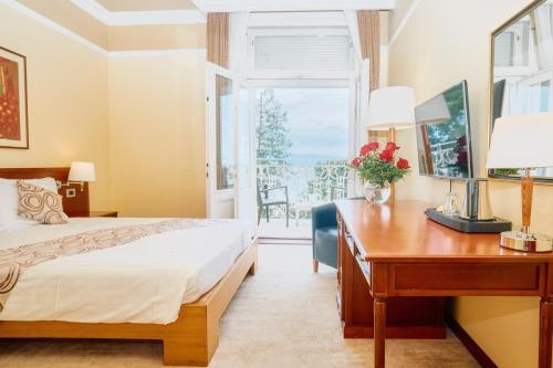 a bedroom with a bed and a desk and a window at BRISTOL Hotel Opatija in Opatija