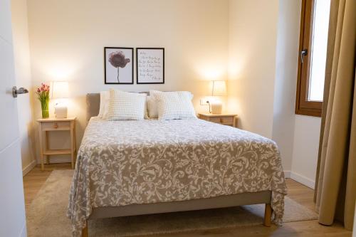 a bedroom with a bed and two tables with lamps at Apartamentos Canterías in Cáceres