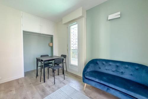 Cette chambre comprend un lit bleu, une table et des chaises. dans l'établissement Flexliving - Splendid whole apartment - Croix Nivert, à Paris