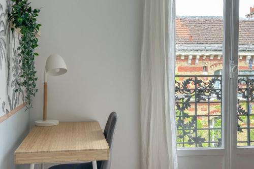 une table et une chaise à côté d'une fenêtre dans l'établissement Flexliving - Whole flat - Balard, à Paris