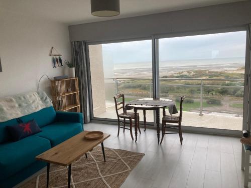 un salon avec un canapé bleu et une table dans l'établissement Studio front de mer 8eme etage, à Le Touquet-Paris-Plage
