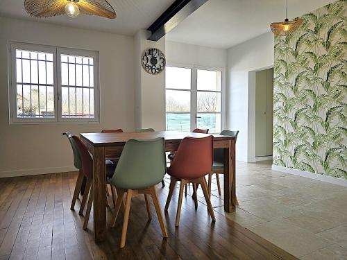 a dining room table with chairs and a clock on the wall at Belle Villa au cœur du frontonnais - Cœur de village - Piscine, jardin et terrasses privés - Climatisation - 8 personnes - 5 lits in Fronton