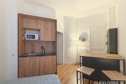 une petite cuisine avec un évier et un micro-ondes dans l'établissement Flexliving - Studio - La Fayette, à Paris