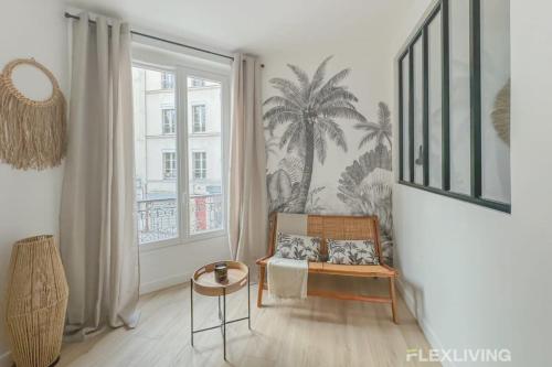 - un salon avec une chaise et une fresque murale de palmiers dans l'établissement Flexliving - studio - Guénot, à Paris