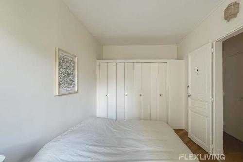une chambre blanche avec un lit et un placard dans l'établissement Flexliving - whole flat - Mesnil, à Paris