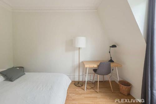 une chambre avec un lit et un bureau avec une chaise dans l'établissement Flexliving - whole - Paris 18, à Paris