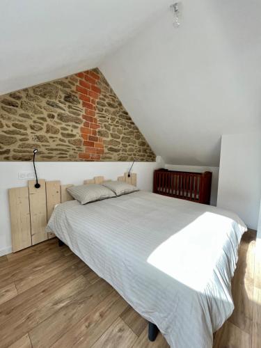 une chambre avec un grand lit avec un mur de briques dans l'établissement Maison cosy proche Cancale et Mont-Saint-Michel, à Saint-Méloir-des-Ondes