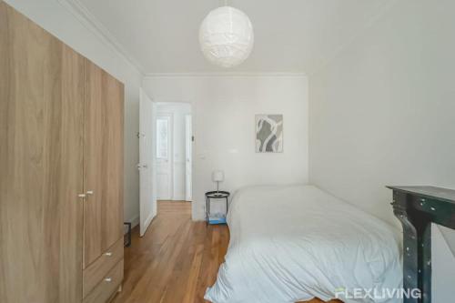 - une chambre blanche avec un lit et une armoire en bois dans l'établissement Flexliving - whole flat - Sophie Germain, à Paris