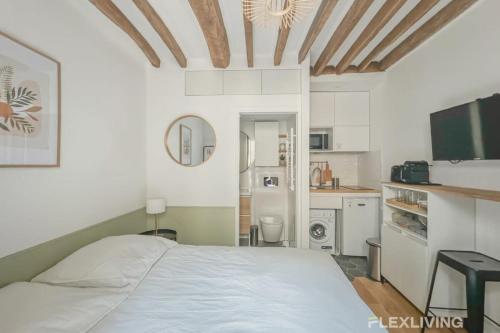 Cet appartement comprend une chambre avec un lit blanc et une cuisine. dans l'établissement Flexliving - Studio - Petits Carreaux - Paris 2, à Paris