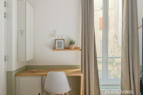 d'un bureau avec une chaise blanche à côté d'une fenêtre. dans l'établissement Flexliving - Studio - Petits Carreaux - Paris 2, à Paris