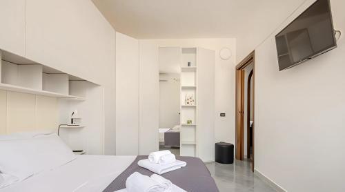 Habitación blanca con cama y TV de pantalla plana. en KuMmìe - Casa Vacanze, en Lecce