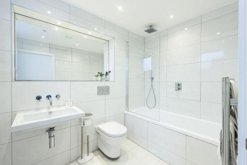 a white bathroom with a sink and a toilet and a tub at 1 Island Reach in Newquay