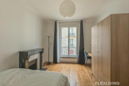 - une chambre avec un lit, une cheminée et une fenêtre dans l'établissement Flexliving - room - Sophie Germain, à Paris
