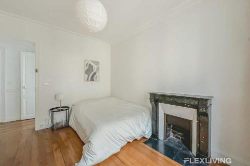 une chambre blanche avec un lit et une cheminée dans l'établissement Flexliving - room - Sophie Germain, à Paris