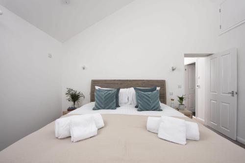 a white bedroom with a large bed with blue pillows at Poldreth - situated above the golden sand and rolling waves of Porthtowan Beach in Porthtowan