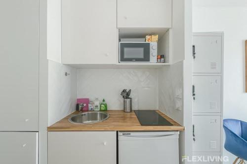 une petite cuisine avec un évier et un micro-ondes dans l'établissement Flexliving - studio - versailles, à Paris