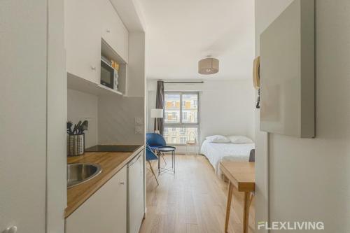 - une cuisine avec un évier et une table dans une chambre dans l'établissement Flexliving - studio - versailles, à Paris