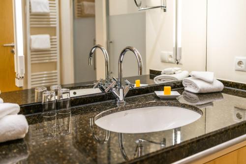a bathroom counter with a sink and a mirror at Berghotel Rehlegg in Ramsau