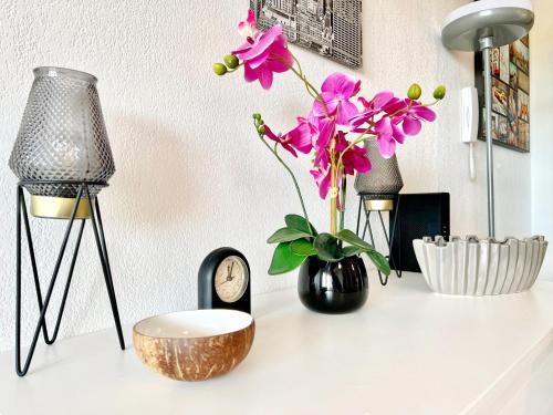 a table with a vase of flowers and a clock at L'Écrin Zen, Privé-Parking-CLIM-WIFI-4 pers in Istres