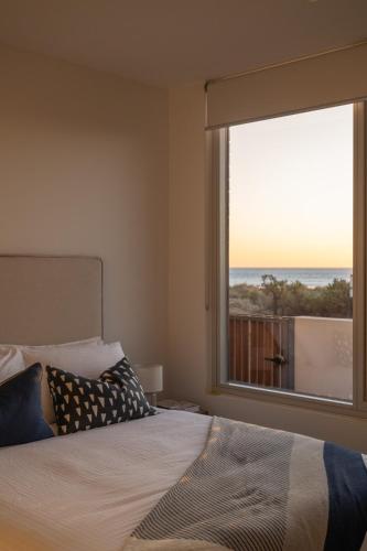 a bedroom with a bed and a large window at Sea Dunes Luxury Apartments in Moana