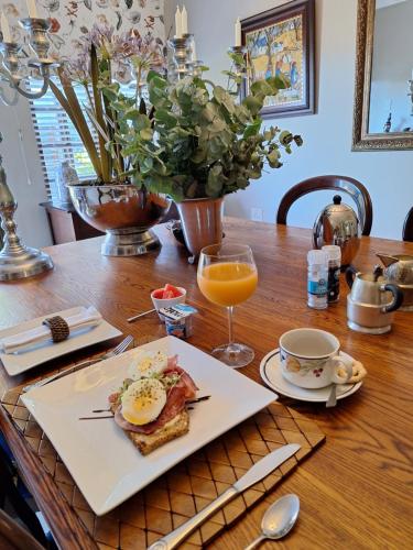 a table with a plate of food and a glass of orange juice at Bella's B&B in Vryheid