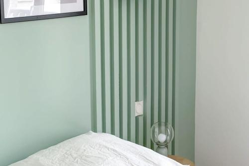 - une chambre avec un mur vert rayé et un lit dans l'établissement Flexliving - whole flat - Echiquier, à Paris