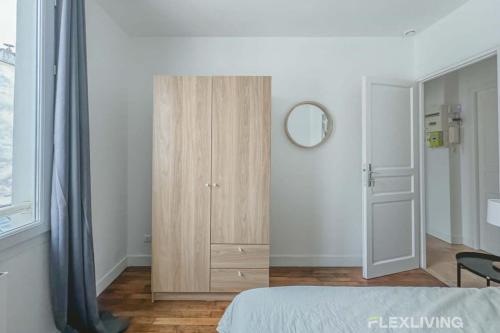 - une chambre avec une armoire en bois à côté d'une fenêtre dans l'établissement Flexliving - room - Saint Martin, à Paris