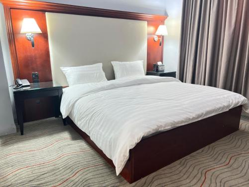 a large bed in a hotel room with two tables at Alqalah Restotel فندق ومطعم القلعة in Kerak